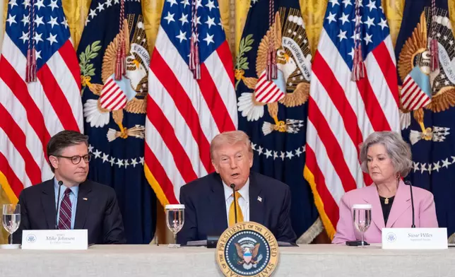President Donald Trump speaks, accompanied by House Speaker Mike Johnson of La., left, and White House chief of staff Susie Wiles during a board meeting of the John F. Kennedy Memorial Center For The Performing Arts in the East Room of the White House, Monday, March 16, 2026, in Washington. (AP Photo/Alex Brandon)