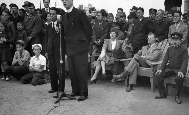 FILE - Father Edward J. Flanagan, founder of Boy's Town, Nebraska, speaks into a microphone at Meiji Stadium in Tokyo, May 28, 1947 during a Japanese Boy Scout Jamboree. At right, wearing his school uniform, is Crown Prince Akahito. (AP Photo/Charles Gorry, File)