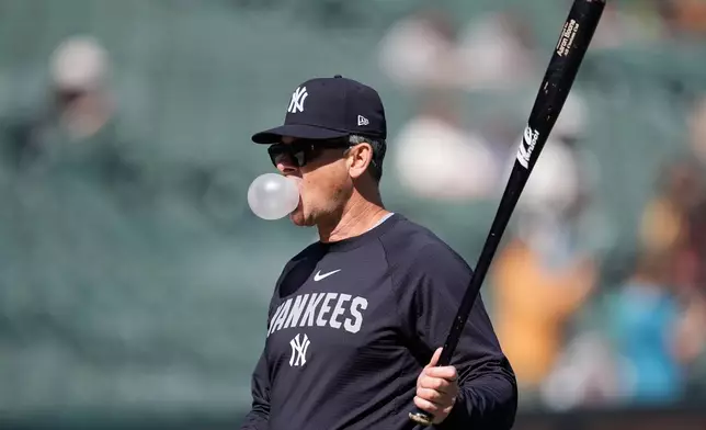 New York Yankees manager Aaron Boone blows a bubble as he watches players take batting practice before a baseball game against the San Francisco Giants in San Francisco, Saturday, March 28, 2026. (AP Photo/Jeff Chiu)