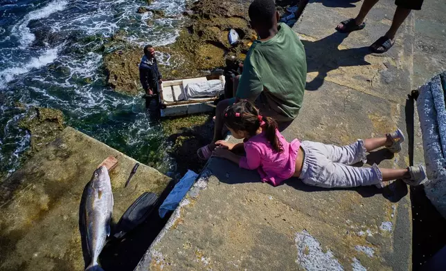 People watch as fishermen pull their catch from the sea during a blackout in Havana, Sunday, March 22, 2026. (AP Photo/Ramon Espinosa)