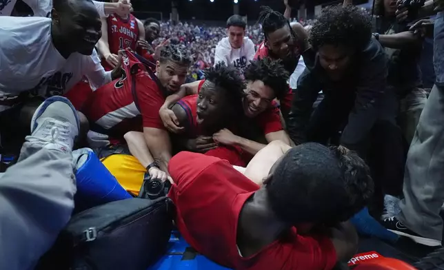 St. John's players celebrate after defeating Kansas a game in the second round of the NCAA college basketball tournament Sunday, March 22, 2026, in San Diego. (AP Photo/Marcio Jose Sanchez)