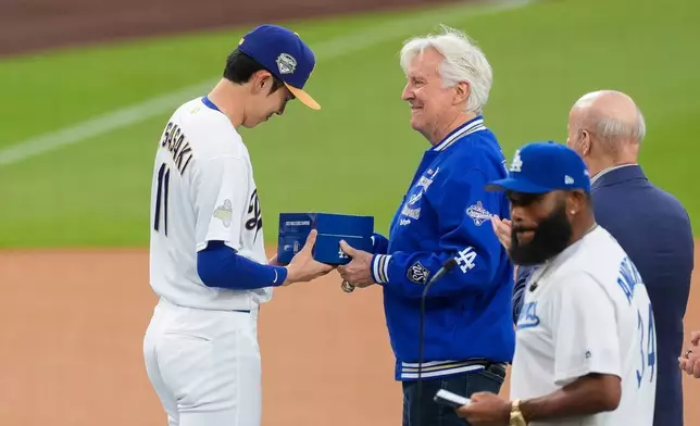 Los Angeles Dodgers Roki Sasaki receives his ring from Los Angeles Dodgers owner Mark Walter during a World Series Champion ring ceremony prior to a baseball game against the Arizona Diamondbacks, Friday, March 27, 2026, in Los Angeles. (AP Photo/Caroline Brehman)