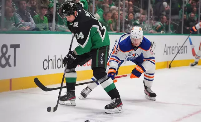 Dallas Stars left wing Jamie Benn (14) and Edmonton Oilers defenseman Connor Murphy, right skate for the puck during the first period of an NHL hockey game, Thursday, March 12, 2026, in Dallas. (AP Photo/LM Otero)