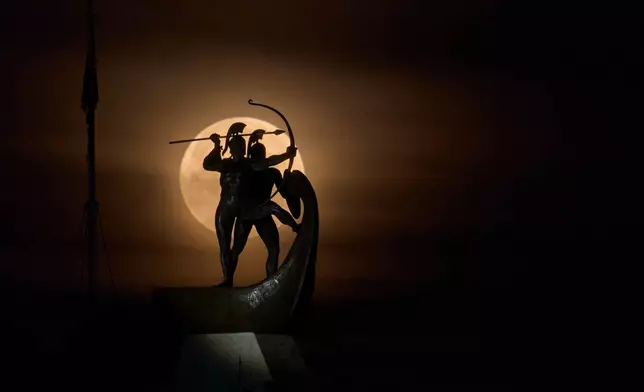 The Worm Moon sets behind the Monument of the Salamis Fighters, also known as Salaminomachoi, on Tuesday, March 3, 2026, on Salamina island, Greece, honoring the ancient Greeks who died in the naval Battle of Salamis in 480 B.C. (AP Photo/Petros Giannakouris)