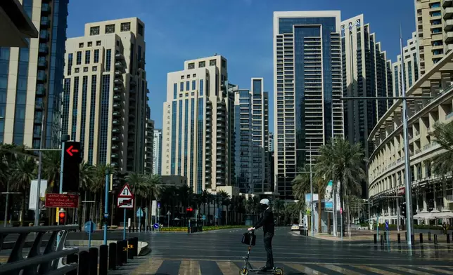 A man rides a battery powered scooter on a deserted road in Downtown Dubai, United Arab Emirates, Sunday, March 1, 2026. (AP Photo/Altaf Qadri)