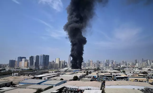 A black plume of smoke rises from a warehouse at the industrial area of Sharjah City in the United Arab Emirates following reports of Iranian strikes in Dubai, United Arab Emirates, Sunday, March 1, 2026. (AP Photo/Altaf Qadri)