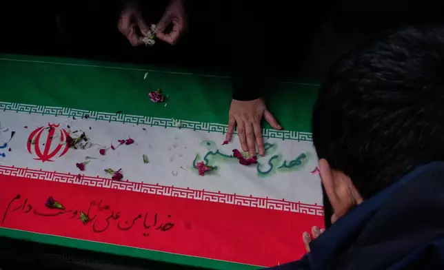 Relatives mourn over the flag draped coffin of Mehdi Hosseini who was killed in a U.S.-Israeli strike during his burial ceremony at Behesht-e Zahra cemetery in Tehran, Iran, Monday, March 9, 2026. (AP Photo/Vahid Salemi)