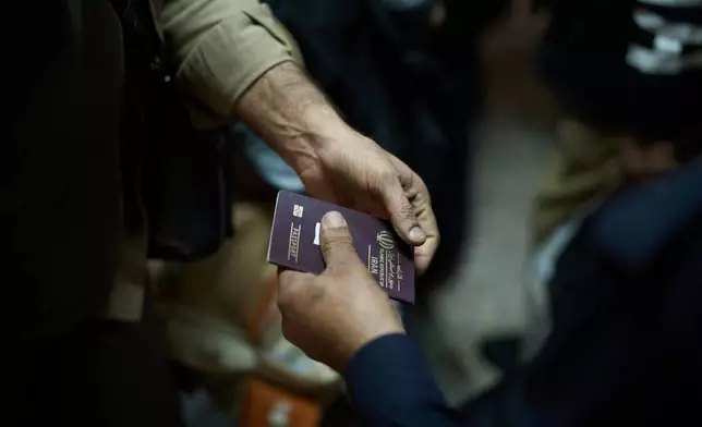 An Iraqi border police officer checks the passport of a man arriving from Iran as he crosses the Shalamcheh border crossing between Iran and Iraq, near Basra, Iraq, Sunday, March 29, 2026. (AP Photo/Leo Correa)