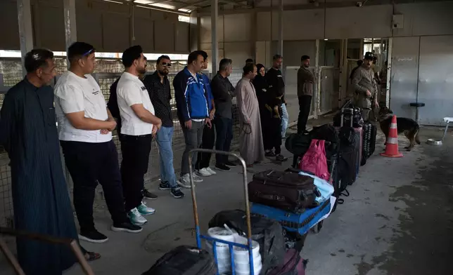 People who arrived from Iran wait in line prior to having their belongings checked by a sniffer dog as they cross the Shalamcheh border crossing between Iran and Iraq, near Basra, Iraq, Sunday, March 29, 2026. (AP Photo/Leo Correa)