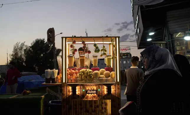 A street vendor prepares fruit juice at his stand in a street market at dusk in Basra, Iraq, Saturday, March 28, 2026. (AP Photo/Leo Correa)