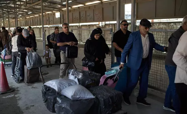 Carrying their belongings, people who arrived from Iran cross the Shalamcheh border crossing between Iran and Iraq, near Basra, Iraq, Sunday, March 29, 2026. (AP Photo/Leo Correa)