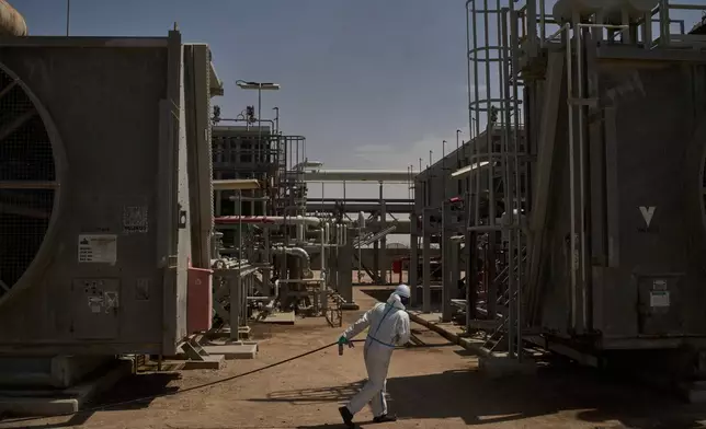 A worker pulls a hose as he works at a degassing station in Zubair oil field, whose operations have being reduced due to the Mideast war triggered by the U.S. and Israeli attacks on Iran, near Basra, Iraq, Saturday, March 28, 2026. (AP Photo/Leo Correa)