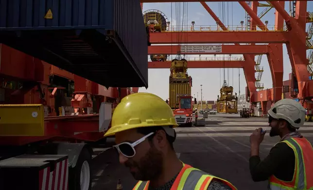 Dockworkers unload cargo containers into trucks at Umm Qasr Port, a deep-water port, in the city of Umm Qasr, Iraq, Friday, March 27, 2026. (AP Photo/Leo Correa)