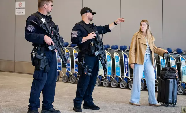 A traveler speaks to police officers at Los Angeles International Airport on Monday, March 23, 2026, in Los Angeles. (AP Photo/Ethan Swope)