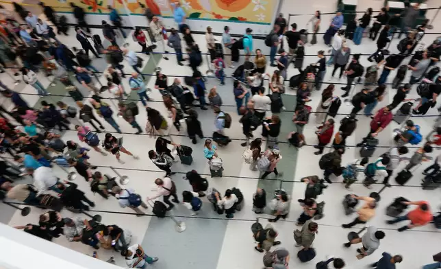 Travelers wait in long security checkpoint lines at George Bush Intercontinental Airport Friday, March 27, 2026, in Houston. (AP Photo/David J. Phillip)