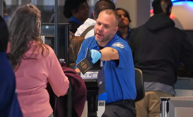 A TSA agent hands a passport back to a passenger at the security checkpoint in Pittsburgh International Airport Monday, March 30, 2026. (AP Photo/Gene J. Puskar)