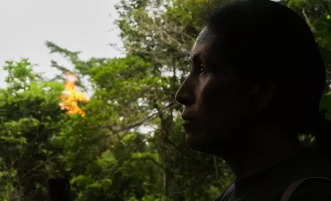Salomé Aranda walks as a gas flare burns in the background in Sucumbios, Ecuador, Friday, March 6, 2026. (AP Photo/Dolores Ochoa)