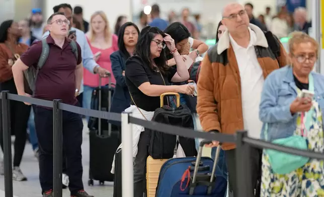 Passengers wait in a security checkpoint line at George Bush Intercontinental Airport, Wednesday, March 25, 2026, in Houston. (AP Photo/David J. Phillip)