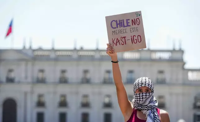 A woman holds a banner that reads in Spanish, "Chile does not deserve this punishment," a pun in reference to Chile's President-elect Jose Antonio Kast, during an International Women's Day protest in Santiago, Chile, Sunday, March 8, 2026. (AP Photo/Esteban Felix)