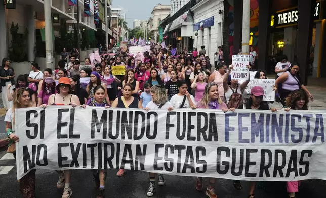 People hold a banner that reads in Spanish, "If the world were feminist, these wars would not exist" during a march marking International Women's Day in Asuncion, Paraguay, Sunday, March 8, 2026. (AP Photo/Jorge Saenz)