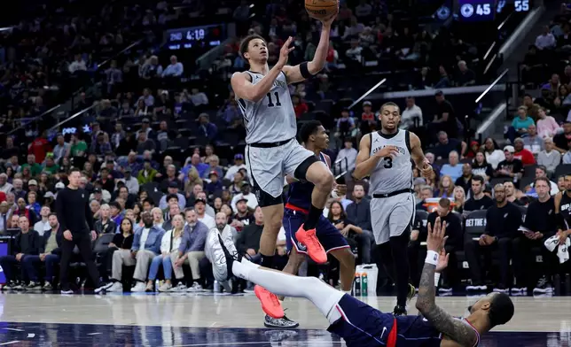 San Antonio Spurs forward Carter Bryant (11) is fouled by Los Angeles Clippers forward John Collins, bottom, during the first half of an NBA basketball game Monday, March 16, 2026, in Inglewood, Calif. (AP Photo/Ryan Sun)