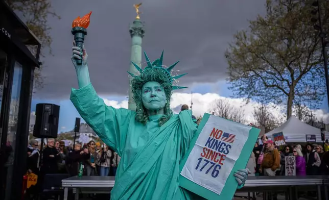 A woman dressed as the Statue of Liberty takes part in the "No Kings" protest in Paris, France, Saturday, March 28, 2026. (AP Photo/Aurelien Morissard)