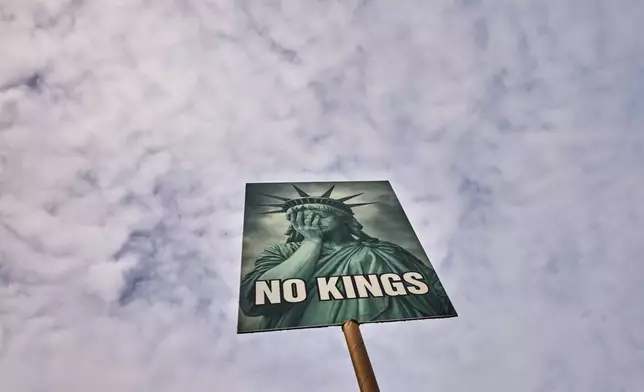 A woman shows a poster as she attends a No Kings Protest against the US government and President Donald Trump in Berlin, Germany, Saturday, March 28, 2026. (AP Photo/Markus Schreiber)
