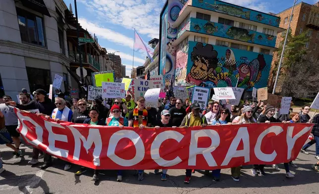 Demonstrators march through the Country Club Plaza shopping district during a "No Kings" protest Saturday, March 28, 2026, in Kansas City, Mo. (AP Photo/Charlie Riedel)