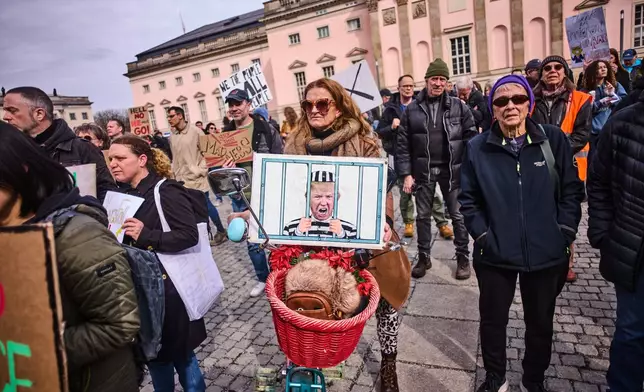 A woman holds a poster showing President Donald Trump behind bars as she attends a No Kings Protest against the US government in Berlin, Germany, Saturday, March 28, 2026. (AP Photo/Markus Schreiber)