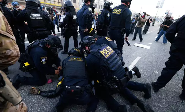 Police detain a protestor near the Metropolitan Detention Center in downtown Los Angeles during a "No Kings" protest Saturday, March 28, 2026. (AP Photo/Jill Connelly)