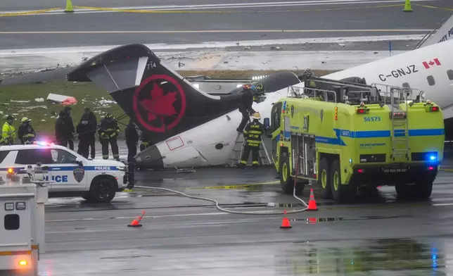 Firefighters and investigators examine the site, Monday, March 23, 2026, where an Air Canada jet came to rest after colliding with a Port Authority firetruck at LaGuardia Airport, after landing Sunday night in New York. (AP Photo/Seth Wenig)
