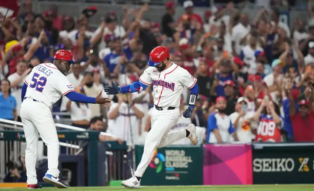 Dominican Republic's Austin Wells is congratulated by third base coach Carlos Febles as he heads for home after hitting a three-run home run to end the game early in the seventh inning of a World Baseball Classic quarterfinal game against South Korea, Friday, March 13, 2026, in Miami. (AP Photo/Lynne Sladky)