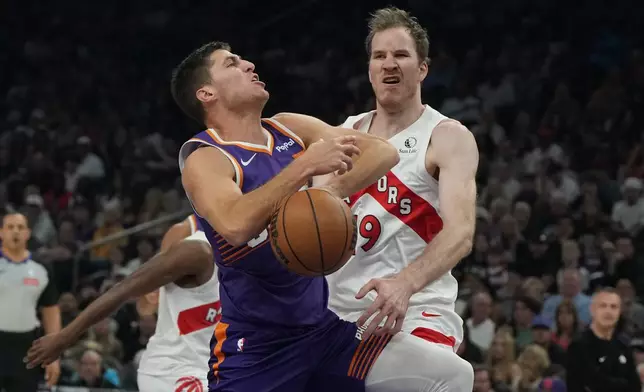 Toronto Raptors center Jakob Poeltl (19) knocks the ball away from Phoenix Suns guard Collin Gillespie during the first half of an NBA basketball game, Sunday, March 23, 2026, in Phoenix. (AP Photo/Rick Scuteri)