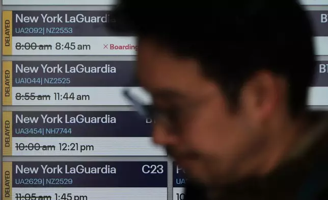 Delayed flight times are displayed at O'Hare International Airport in Chicago, Tuesday, March 24, 2026. (AP Photo/Nam Y. Huh)