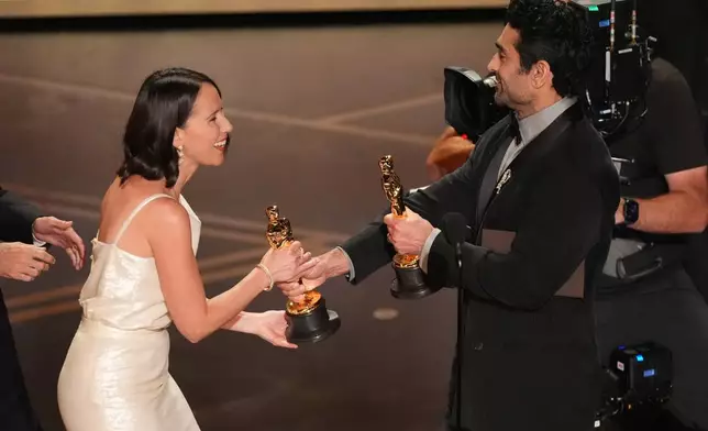 Natalie Musteata, left, accepts the award for live action short film for "Two People Exchanging Saliva" from Kumail Nanjiani during the Oscars on Sunday, March 15, 2026, at the Dolby Theatre in Los Angeles. (AP Photo/Chris Pizzello)