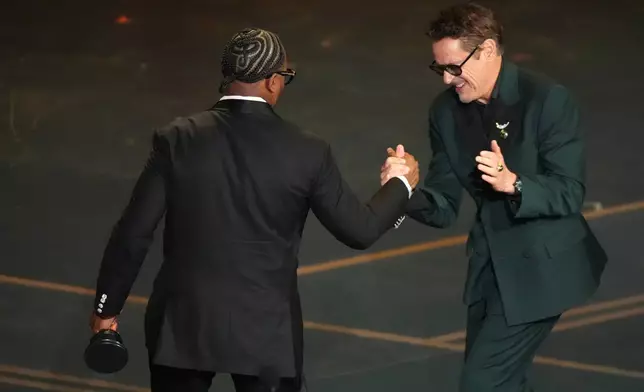 Robert Downey Jr., right, congratulates Ryan Coogler for winning the award for writing (original screenplay) for "Sinners" during the Oscars on Sunday, March 15, 2026, at the Dolby Theatre in Los Angeles. (AP Photo/Chris Pizzello)