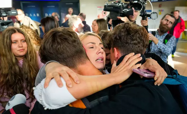 A family hugs after disembarking from an evacuation flight on a commercial airplane from Muscat, Oman, at the Henri Coanda International Airport in Otopeni, Romania, Friday, March 6, 2026. (AP Photo/Vadim Ghirda)