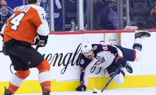 Columbus Blue Jackets' Conor Garland, right, dives for the puck against Philadelphia Flyers' Nick Seeler during the third period of an NHL hockey game Tuesday, March 24, 2026, in Philadelphia. (AP Photo/Matt Slocum)