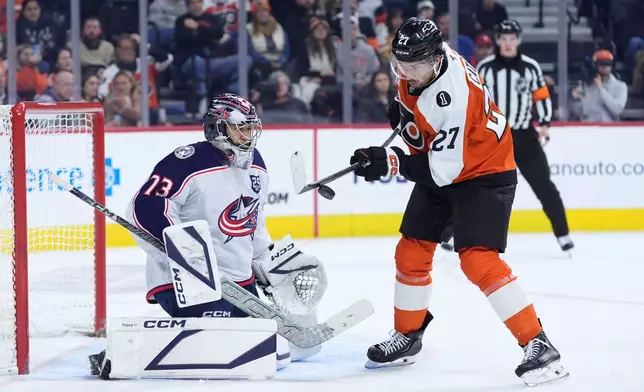 Philadelphia Flyers' Noah Cates, right, tries to get the puck past Columbus Blue Jackets' Jet Greaves during the second period of an NHL hockey game Tuesday, March 24, 2026, in Philadelphia. (AP Photo/Matt Slocum)