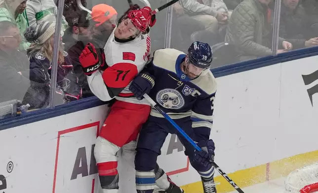 Columbus Blue Jackets' Boone Jenner, right, checks Carolina Hurricanes' Mark Jankowski (77) in the second period of an NHL hockey game in Columbus, Tuesday, March 17, 2026. (AP Photo/Sue Ogrocki)