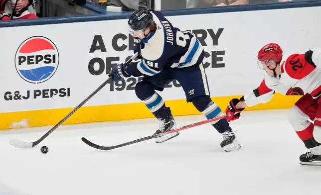 Columbus Blue Jackets' Kent Johnson (91) takes the puck past Carolina Hurricanes' Sebastian Aho (20) in the second period of an NHL hockey game in Columbus, Tuesday, March 17, 2026. (AP Photo/Sue Ogrocki)