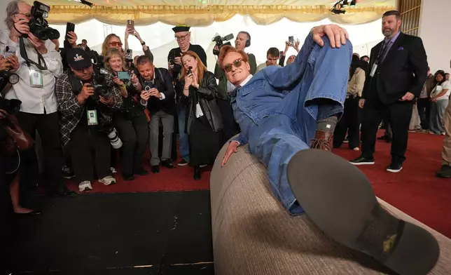 Academy Awards host Conan O'Brien poses atop a roll of red carpet during the annual Oscars red carpet roll out on Wednesday, March 11, 2026, at the Dolby Theatre in Los Angeles. (AP Photo/Chris Pizzello)