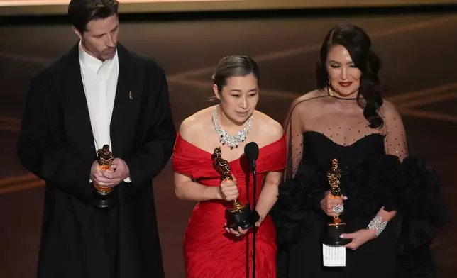 Chris Appelhans, from left, Maggie Kang, and Michelle L.M. Wong accept the award for animated feature film for "K-pop Demon Hunters" during the Oscars on Sunday, March 15, 2026, at the Dolby Theatre in Los Angeles. (AP Photo/Chris Pizzello)