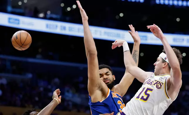Los Angeles Lakers guard Austin Reaves (15) passes the ball to a teammate while being guarded by by New York Knicks center Karl-Anthony Towns during the first half of an NBA basketball game, Sunday, March 8, 2026, in Los Angeles. (AP Photo/Caroline Brehman)