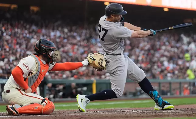 New York Yankees' Giancarlo Stanton, right, hits an RBI single in front of San Francisco Giants catcher Patrick Bailey during the fifth inning of a baseball game in San Francisco, Wednesday, March 25, 2026. (AP Photo/Jeff Chiu)