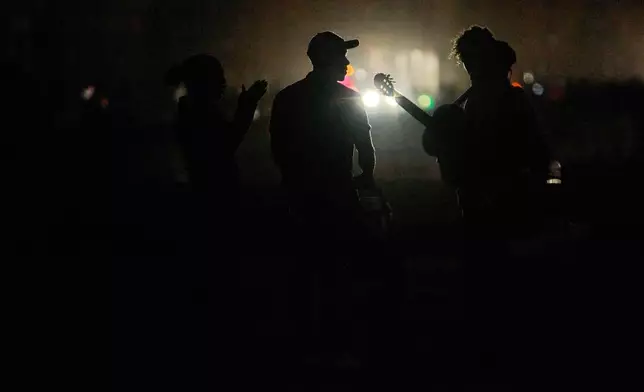 People spend the dark on the Malecon during a blackout in Havana, Cuba, Saturday, March 21, 2026. (AP Photo/Ramon Espinosa)