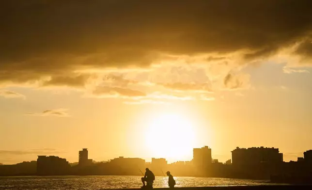 Fishermen are seen on the Malecón seawall at dawn during a blackout in Havana, Cuba, Sunday, March 22, 2026. (AP Photo/Ramon Espinosa)