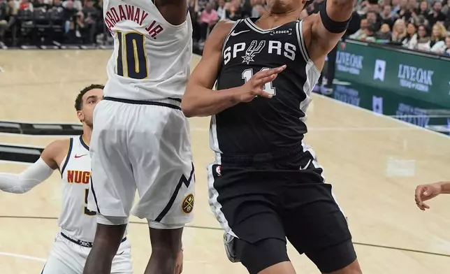 San Antonio Spurs forward Carter Bryant (11) drives to the basket against Denver Nuggets guard Tim Hardaway Jr. (10) during the first half of an NBA basketball game in San Antonio, Thursday, March 12, 2026. (AP Photo/Eric Gay)
