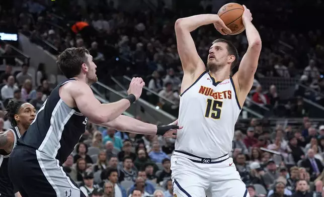 Denver Nuggets center Nikola Jokic (15) shoots over San Antonio Spurs center Luke Kornet, left, during the first half of an NBA basketball game in San Antonio, Thursday, March 12, 2026. (AP Photo/Eric Gay)