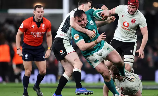 Ireland's Rónan Kelleher, center, is tackled by Wales' players during a Six Nations rugby union match between Ireland and Wales in Dublin, Ireland, Friday, March 6, 2026. (AP Photo/Peter Morrison)